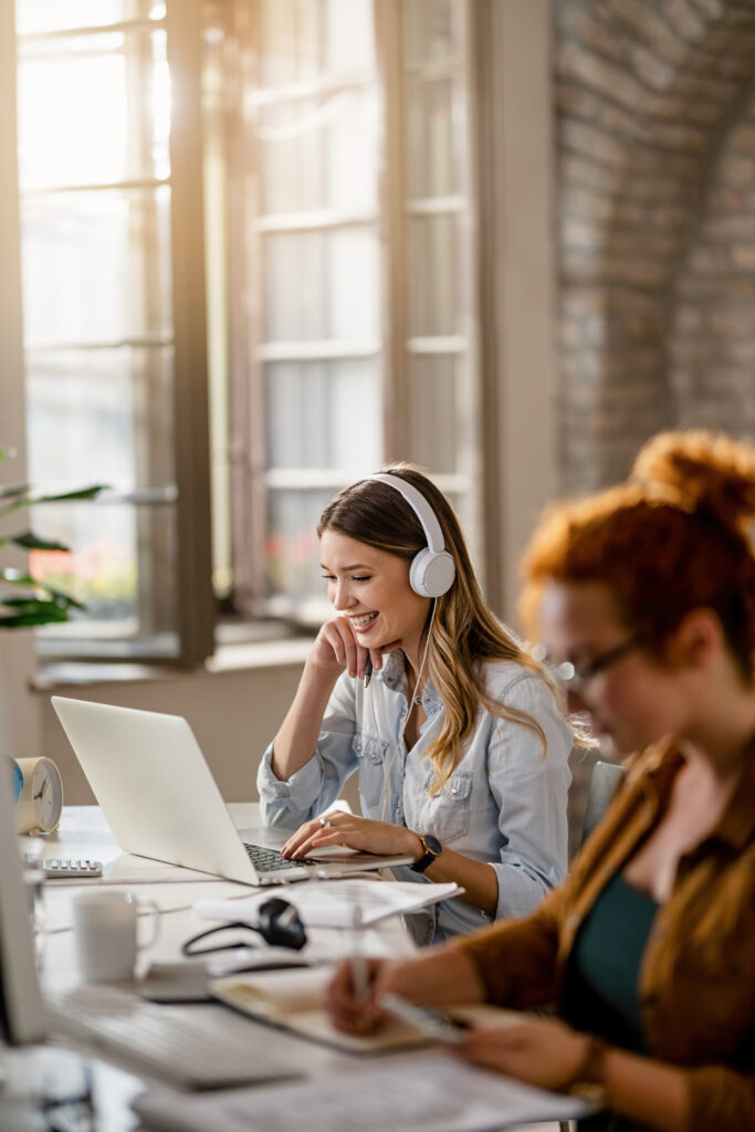 Happy businesswoman with headphones working on laptop in the off